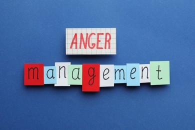 Photo of Sheets of paper with words Anger Management on blue background, flat lay