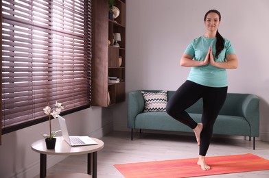 Overweight woman practicing yoga at home, space for text