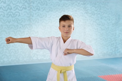 Boy in kimono practicing karate at gym