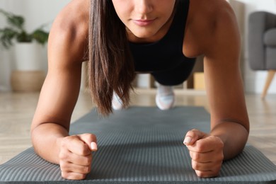Young woman doing plank exercise at home, closeup