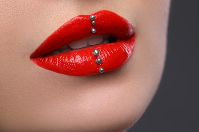 Photo of Young woman with red lips makeup on grey background, closeup