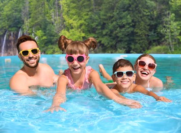 Happy family having fun in outdoor swimming pool at luxury resort on sunny day