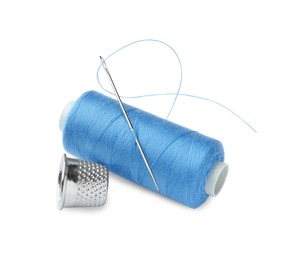 Spool of light blue sewing thread with needle and thimble on white background