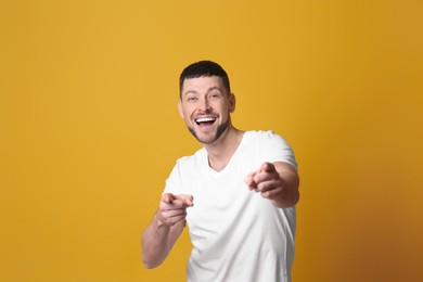 Handsome man laughing on yellow background. Funny joke