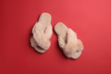 Pair of soft fluffy slippers on red background, top view