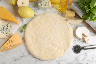Flat lay composition with pizza crust and fresh ingredients on marble table