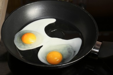 Photo of Cooking eggs for breakfast in frying pan on cooktop, closeup
