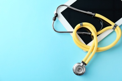 Stethoscope and tablet on color background, top view. Medical equipment