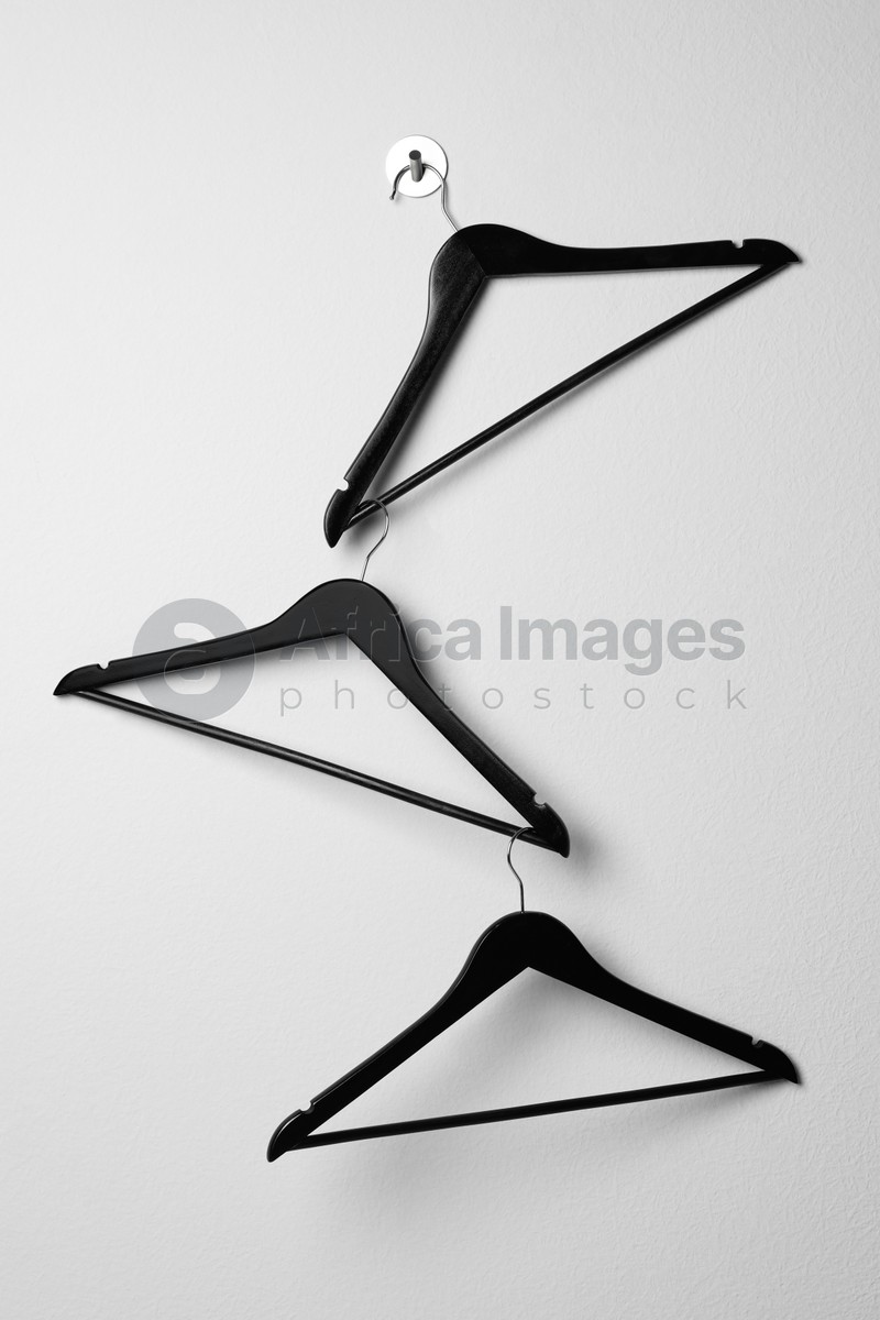 Photo of Empty black clothes hangers on white wall