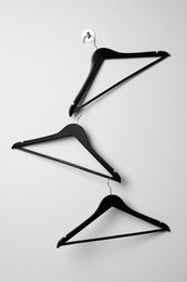 Empty black clothes hangers on white wall