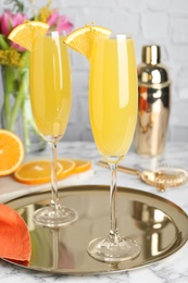 Glasses of Mimosa cocktail with garnish on white marble table