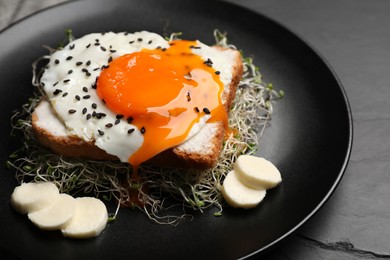 Tasty toast with egg, cheese and microgreens on light black table