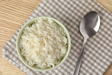 Bowl with tasty cooked rice on wooden table, flat lay