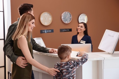 Young family near reception desk in hotel