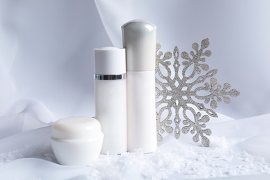 Set of cosmetic products and decorative snow on white fabric. Winter care
