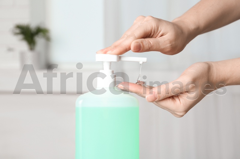 Woman applying antiseptic gel on hand indoors, closeup