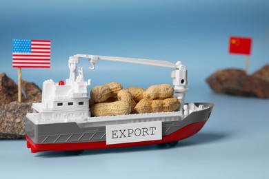 Toy cargo vessel, stones with American and Chinese flags on color background. Export concept