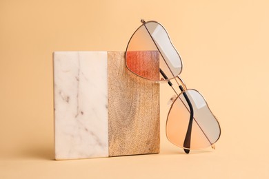 Stylish elegant heart shaped sunglasses on beige background