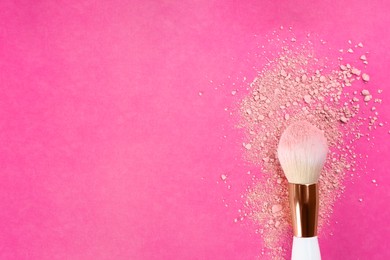 Makeup brush and scattered blush on bright pink background, top view. Space for text