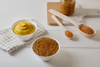 Photo of Bowls and spoons of whole grain mustard with seeds on white wooden table