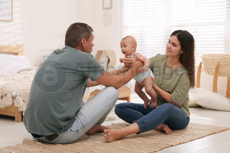 Happy family with their cute baby on floor in bedroom