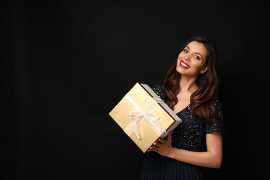 Beautiful woman with Christmas gift on black background