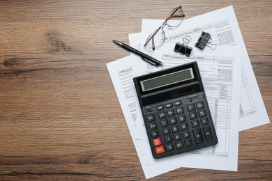 Calculator, documents, glasses and stationery on wooden table, flat lay with space for text. Tax accounting