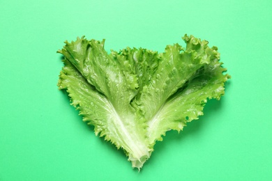 Photo of Leaves of fresh lettuce on green background, top view