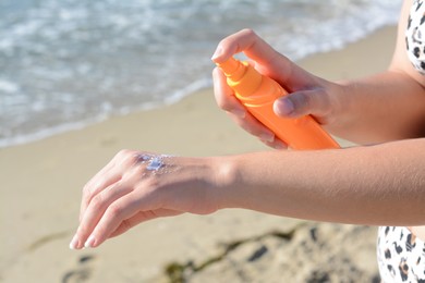 Woman applying sun protection cream on her hand at beach, closeup