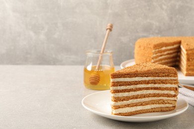 Slice of delicious layered honey cake served on grey table. Space for text