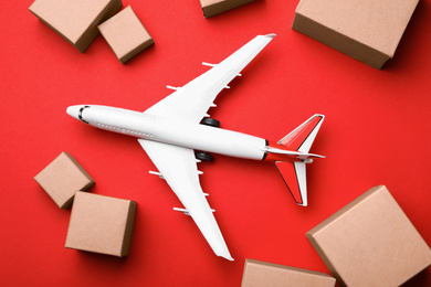 Top view of toy plane with boxes on red background. Logistics and wholesale concept