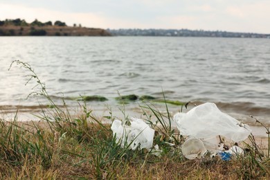 Plastic garbage scattered on grass near river