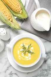 Delicious creamy corn soup served on white marble table, flat lay