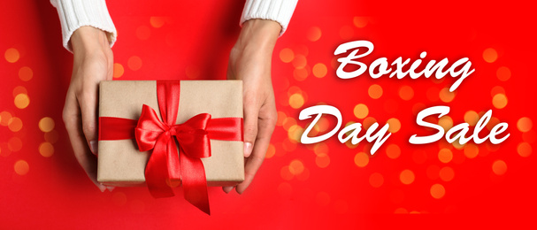 Boxing day sale. Top view of woman with gift on red background, banner design