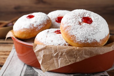 Delicious donuts with jelly and powdered sugar in baking dish on table, closeup