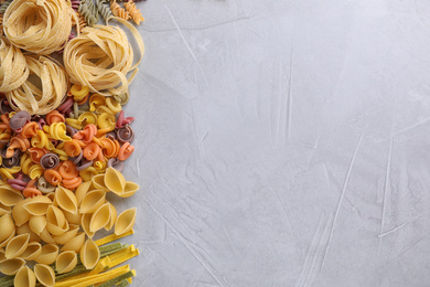 Different types of pasta on light grey table, flat lay. Space for text