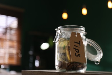 Glass jar with tips on wooden table indoors, closeup. Space for text