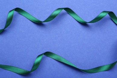 Beautiful green ribbons on blue background, flat lay. Space for text
