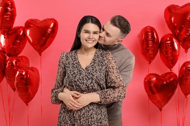 Photo of Lovely couple near heart shaped air balloons on red background. Valentine's day celebration