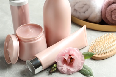 Set of hair cosmetic products, brush and flower on  grey table, closeup
