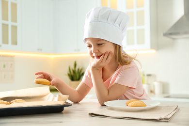 Little girl wearing chef hat baking cookies in kitchen
