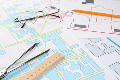 Office stationery and eyeglasses on cadastral maps of territory with buildings