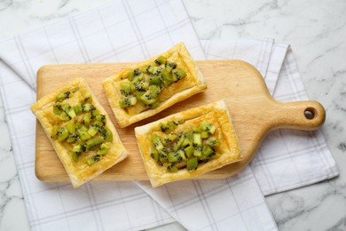 Photo of Fresh tasty puff pastry with kiwi on white marble table, top view