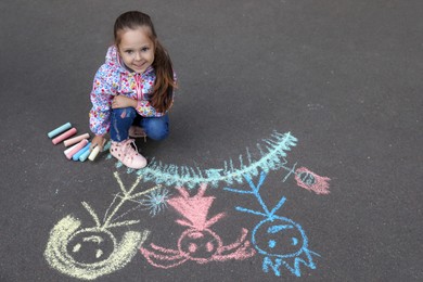 Child drawing family with chalk on asphalt