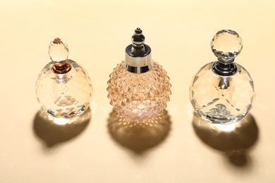 Different elegant perfume bottles on beige background