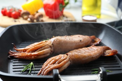 Photo of Cooking fresh squids with rosemary on grill pan, closeup