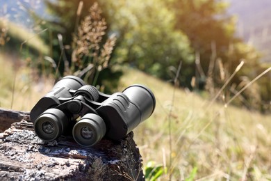 Modern binoculars on wooden surface outdoors, space for text