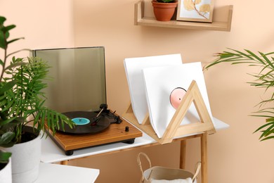 Stylish turntable with vinyl record on wooden table in room