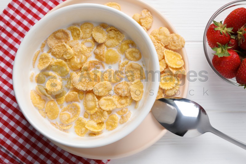 Bowl of tasty corn flakes and strawberries served for breakfast on white wooden table, flat lay