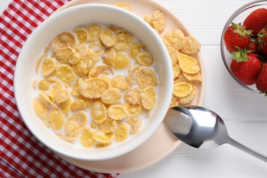 Bowl of tasty corn flakes and strawberries served for breakfast on white wooden table, flat lay